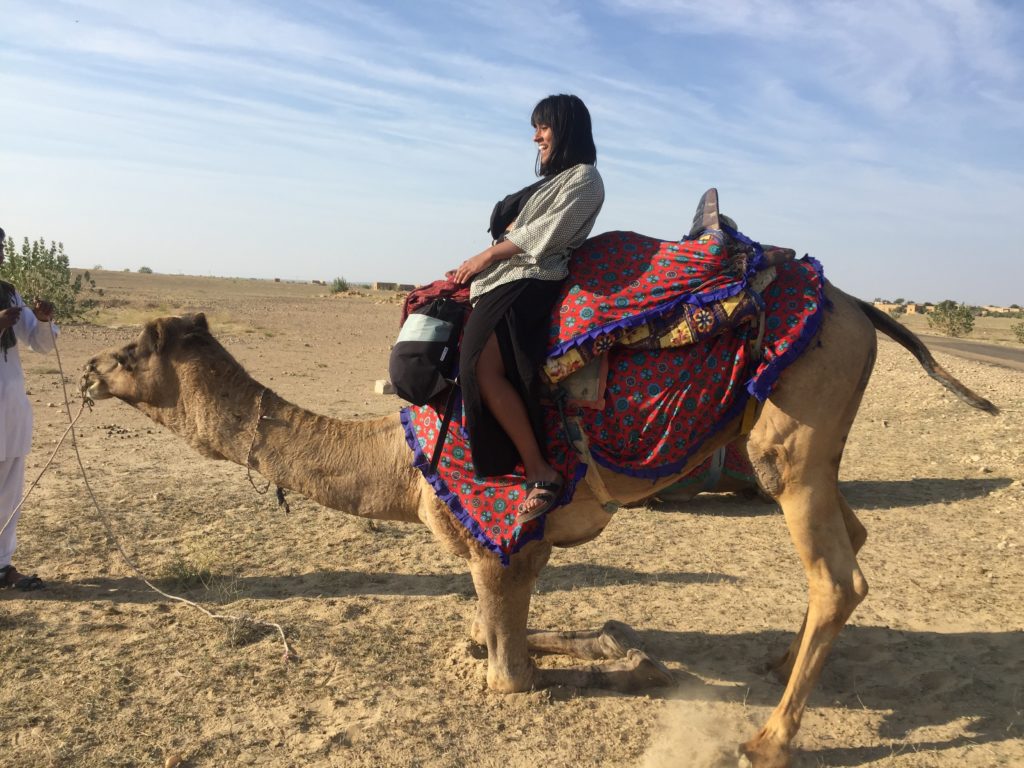 a woman riding a camel in the thar desert